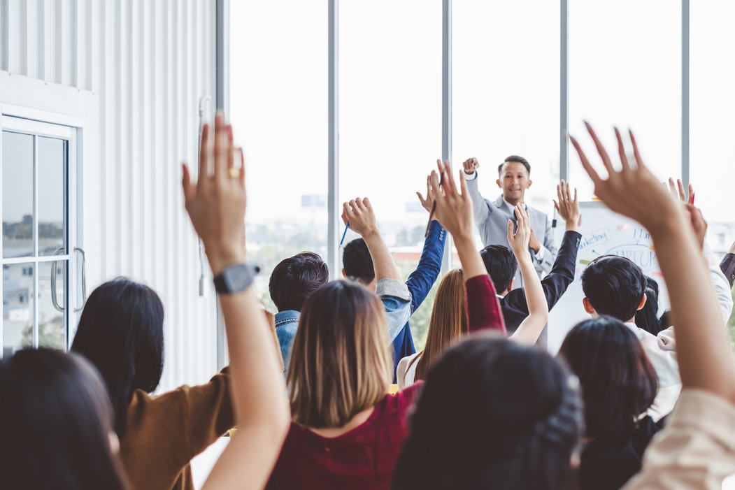 Group of business people raise hands up to agree with speaker in the meeting room seminar